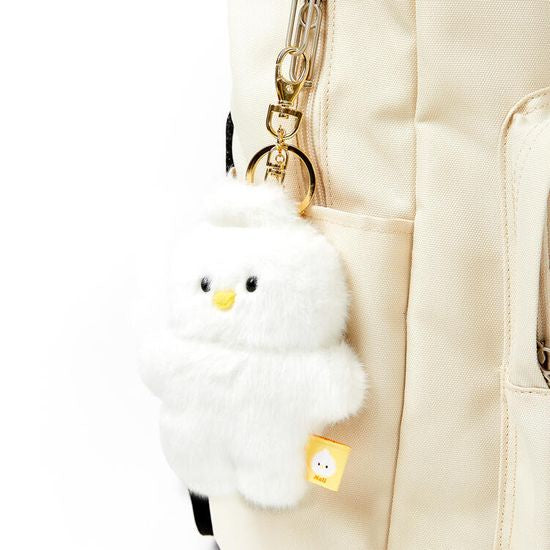 White fluffy keychain attached to a beige backpack