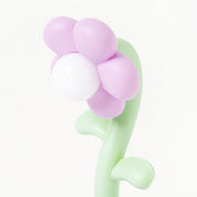 Flower-shaped night lamp with purple petals and green stem on a white background