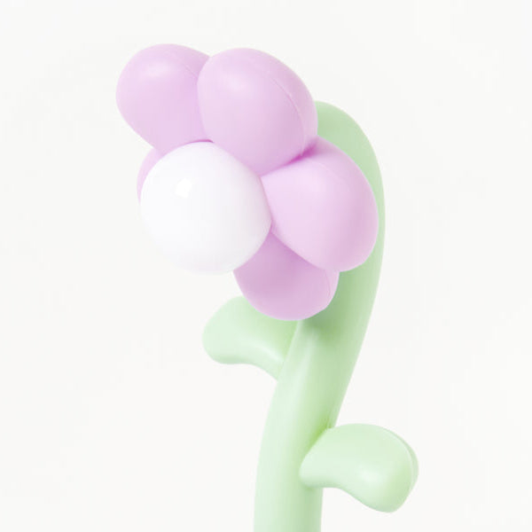 Flower-shaped night lamp with purple petals and green stem on a white background
