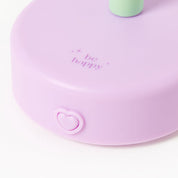 Purple round device with a heart-shaped button and 'be happy' text on a white background