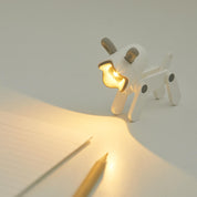 Dog-shaped night light on a white surface with a notebook and pen.