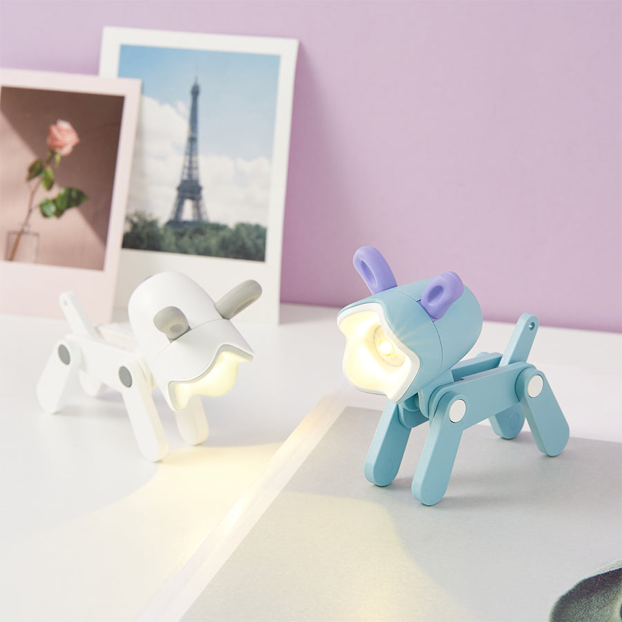 Two small night lights, one white and one blue with a purple accent, on a surface with a blurred background.