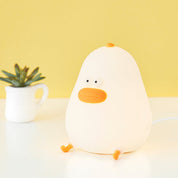 White duck-shaped night light on a white surface with a yellow background