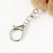 Close-up of a fluffy brown keychain with a metal clasp on a white background