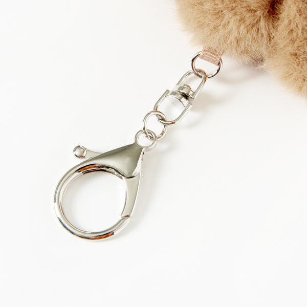 Close-up of a fluffy brown keychain with a metal clasp on a white background