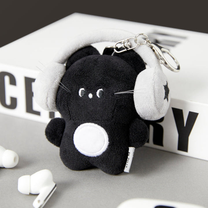 Black cat plush keychain with white accents on a magazine background