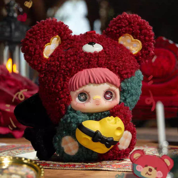 Toy figure with red hair and a yellow heart, surrounded by decorative elements.