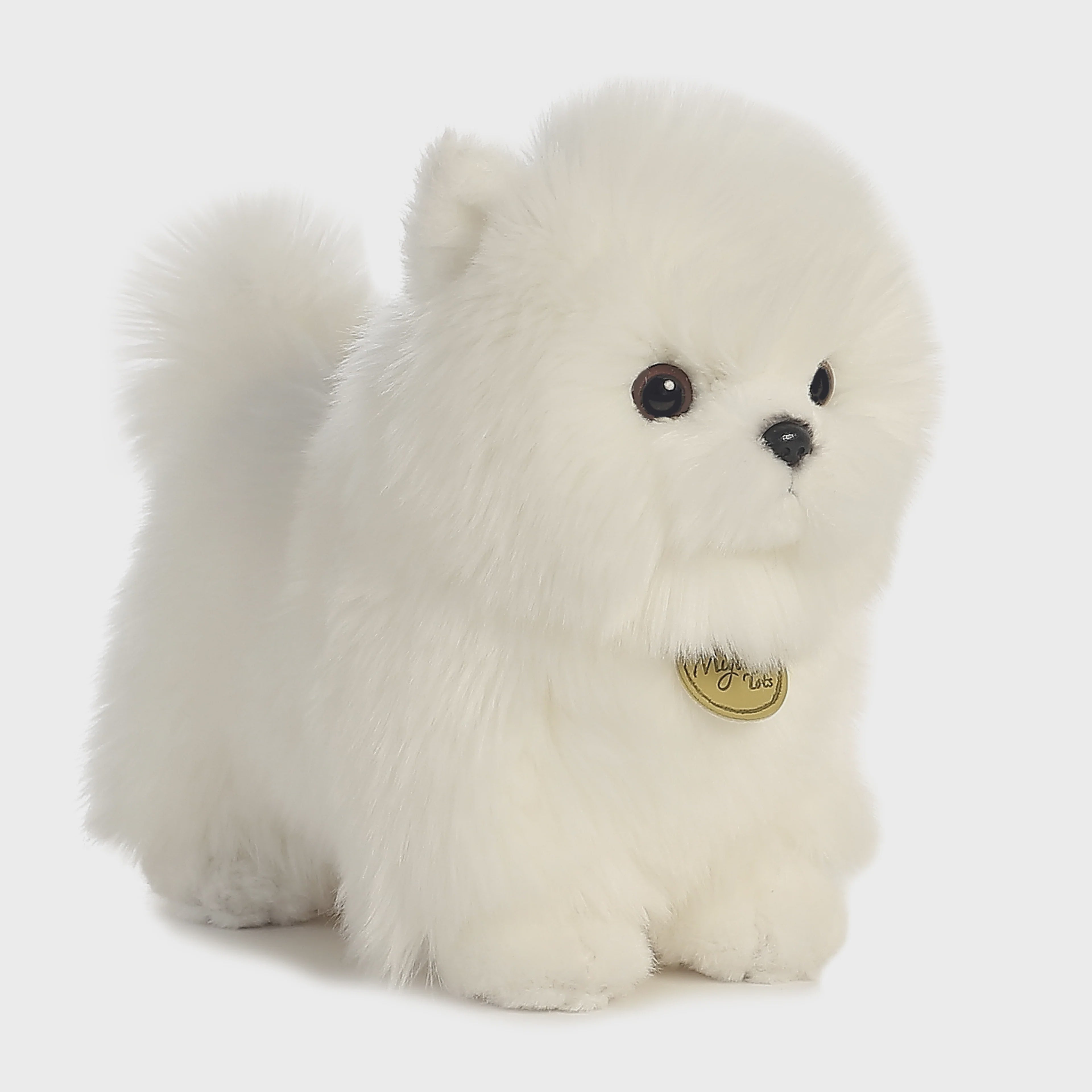 White plush dog toy with a gold tag on a light gray background