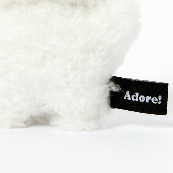 White fluffy keychain with a black 'Adore!' tag on a white background