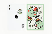 Cartoon character playing cards with a green dinosaur-like creature and a small frog on a white background.