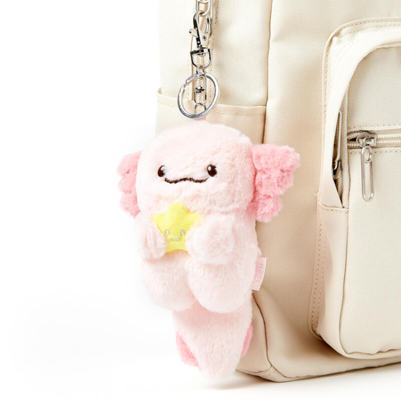 Plush keychain with a star held by a pink creature attached to a beige backpack.